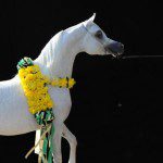 A white horse with flowers on its neck.